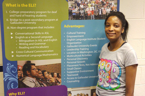 Tyra, a refugee from Zimbabwe, smiles as she stands in front of an English Language Institute banner at Gallaudet University