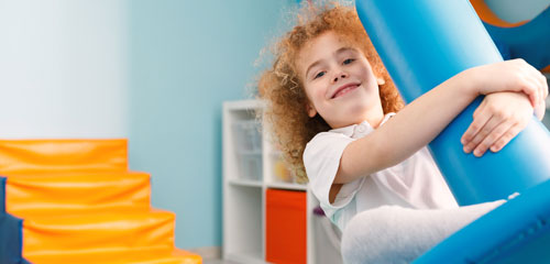 A boy rocks on a toy in a sensory room