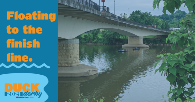 Photograph from DRO's Duck Derby, featuring a river and canoes paddling past a bridge on a sunny day. The canoes are following a group of several hundred rubber ducks. Text over the image reads, 