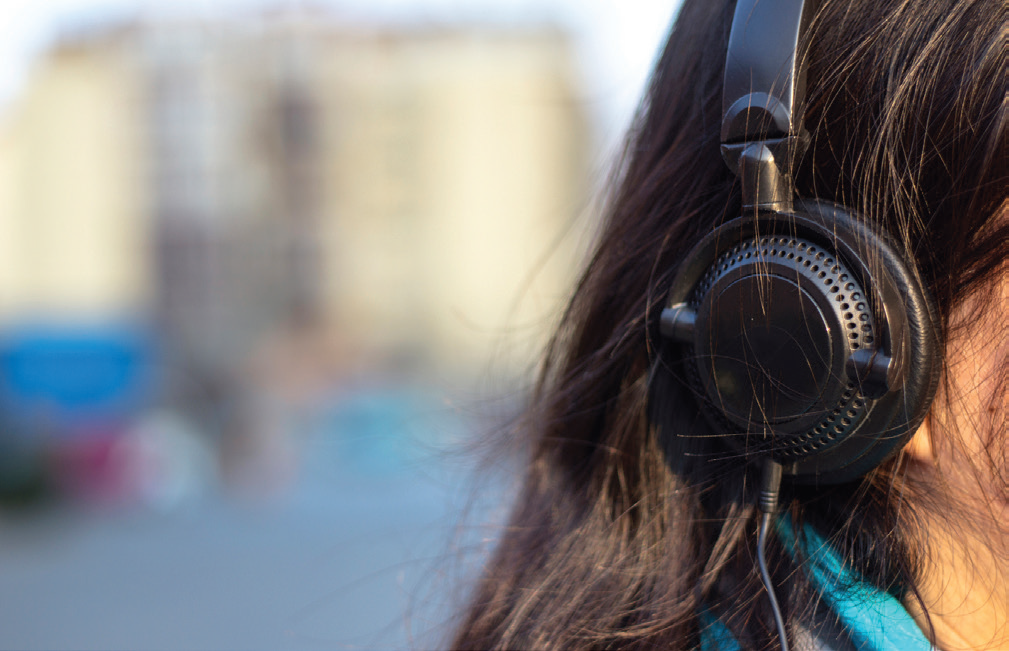 The side of a woman's head, which is covered by earphones.