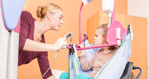 A nurse helps a girl with disabilities as she sits in a lift.