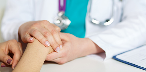 Hands of woman doctor comforting hands of woman patient