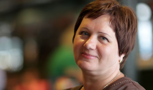 A white woman with short reddish brown hair looks at the camera with a pleasant expression on her face